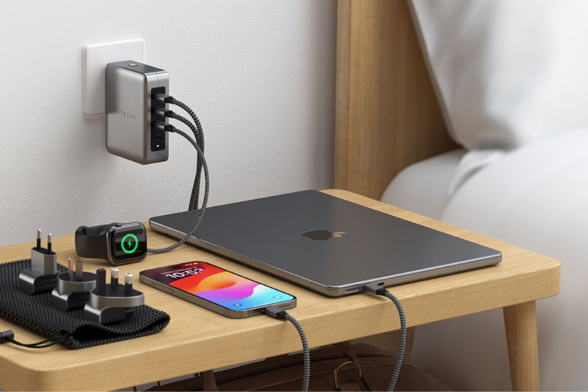 Мережевий зарядний пристрій Satechi 145W Travel Charger з комплектом міжнародних адаптерів, що одночасно заряджає MacBook, iPhone та Apple Watch у готелі.