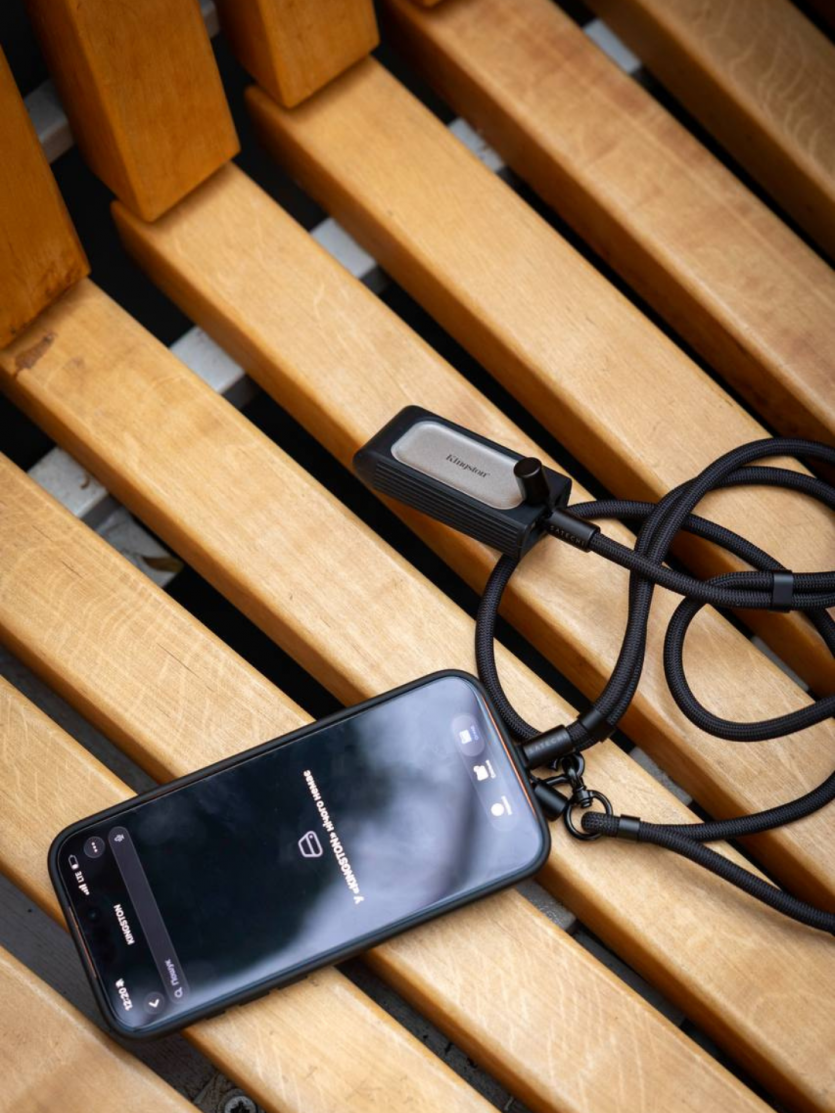 Ремінець-кабель Satechi On-the-Go підключений до iPhone та зовнішнього SSD-накопичувача Kingston для швидкої передачі даних.