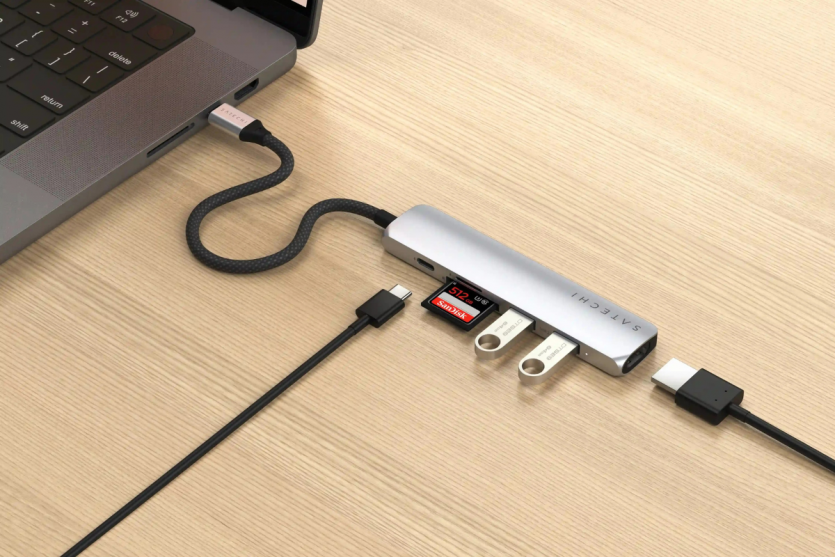 Багатопортовий USB-C хаб Satechi, підключений до MacBook Pro, з під'єднаними флешками, SD-карткою та кабелями.